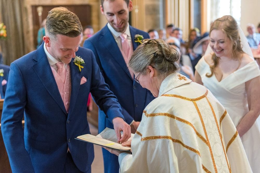 The best man passes the wedding rings to the vicar to be blessed.