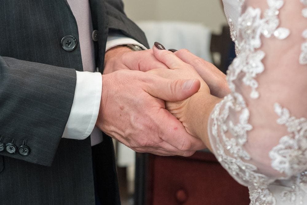 A groom holds his bride's hands tenderly during their ceremony at York Register Office.