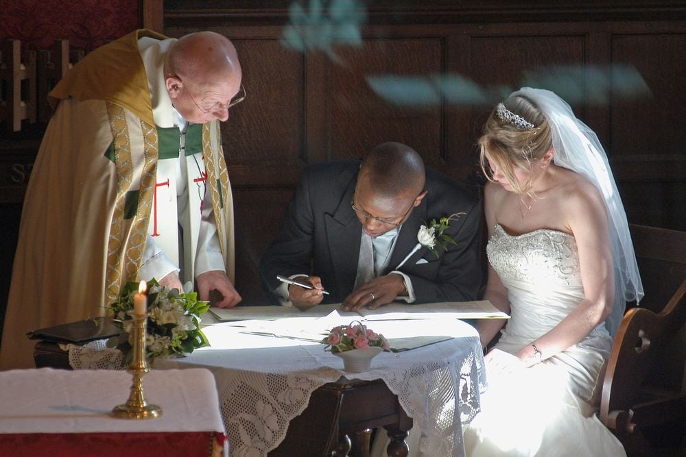 The vicar and Alison watch new husband Michael sign the register at St John the Baptist Church, Stamford Bridge, York.