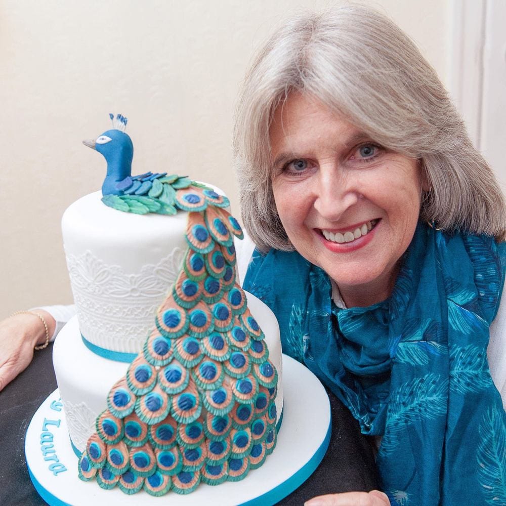 A cake-maker with an elaborate peacock-themed cake.