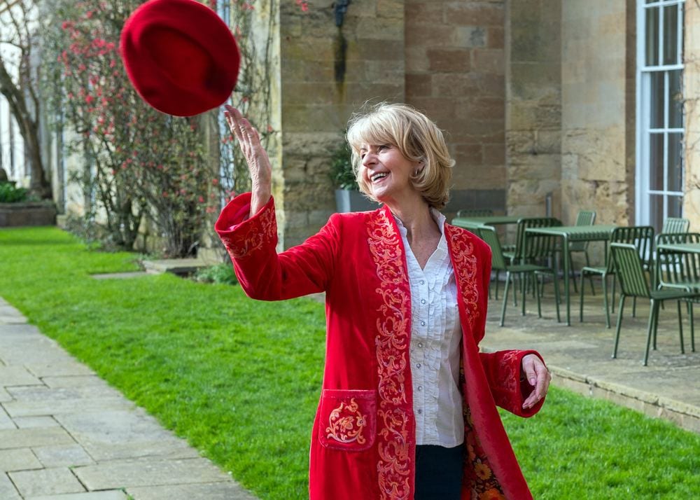 A model in a bright red jacket tosses her beret in the air.