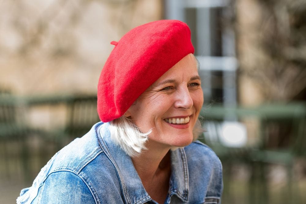 A close-up of a model laughing in a red beret.