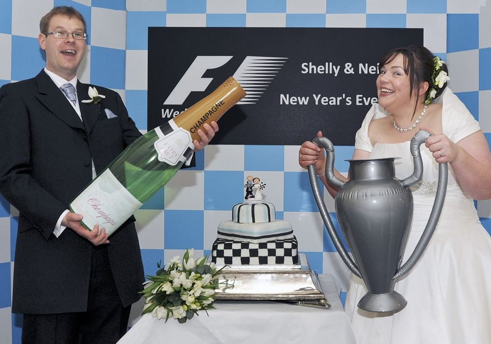 F1 fans Shelley & Neil with F1-inspired props and their wedding cake.