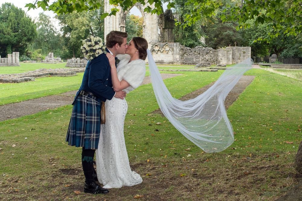 Claire's veil blows in the wind as Hamish kisses her in the Museum Gardens.