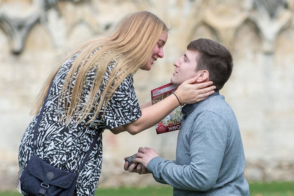 A surprise proposal – he gets down on one knee as she leans in to kiss him.