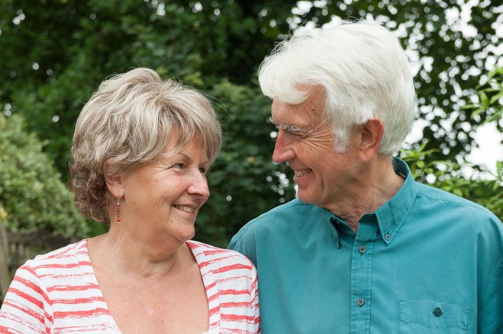 An elderly couple look adoringly at each other.