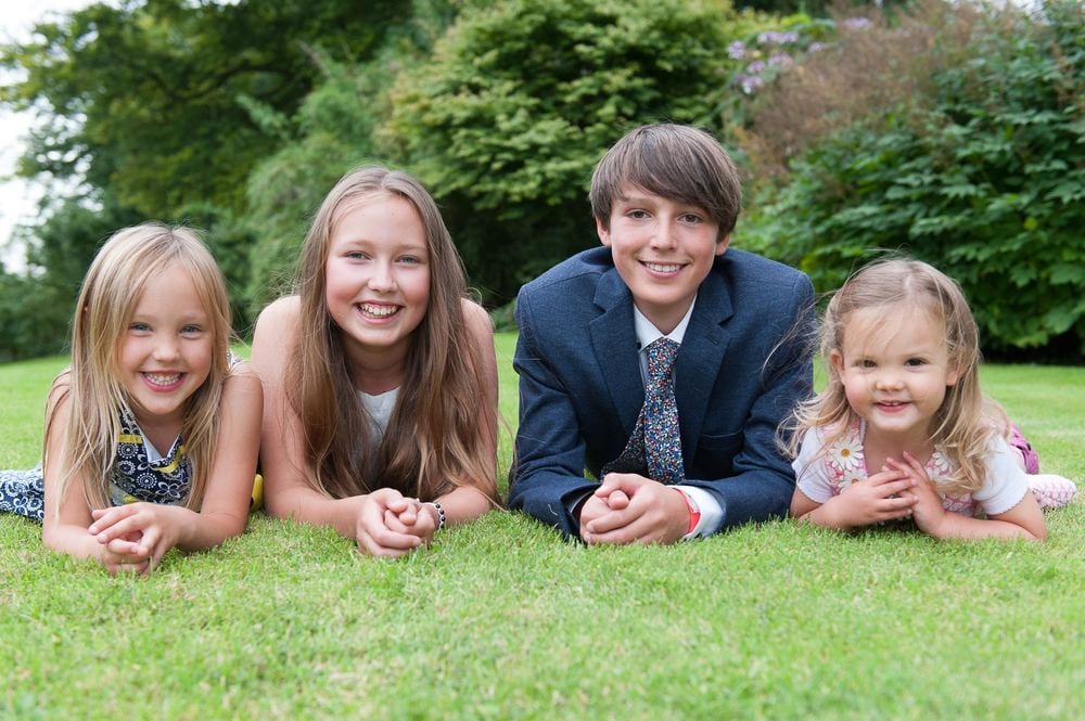 Four children, smartly dressed, lying on their tummies looking to camera.