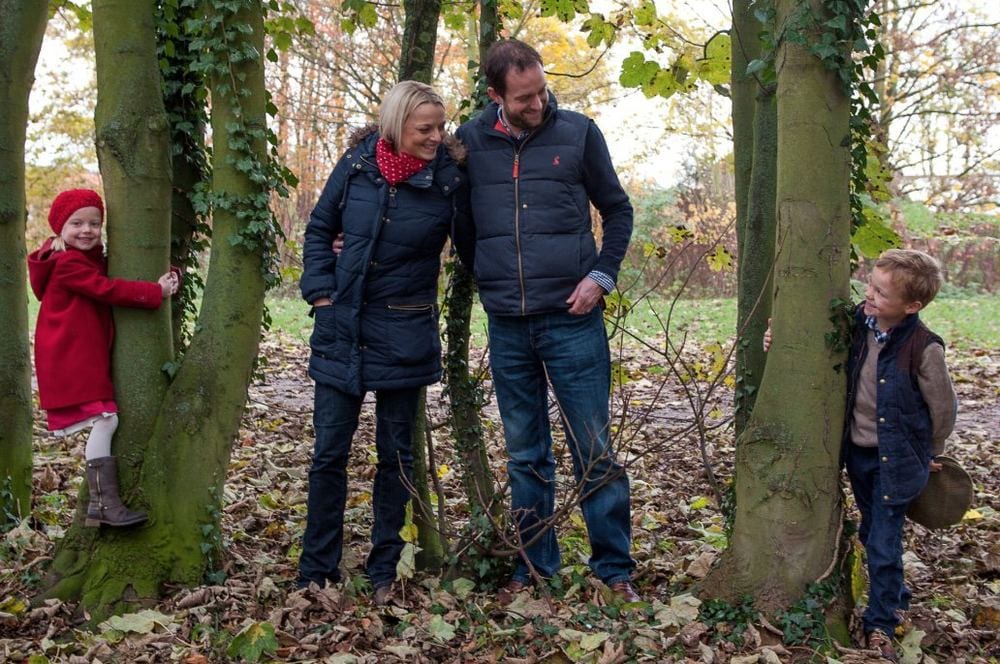 Parents with their two small children in an autumnal woodland.