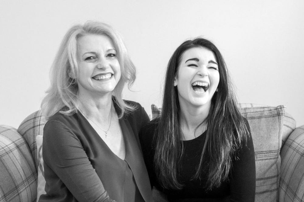 A black-and-white portrait of a mum and daughter laughing together.