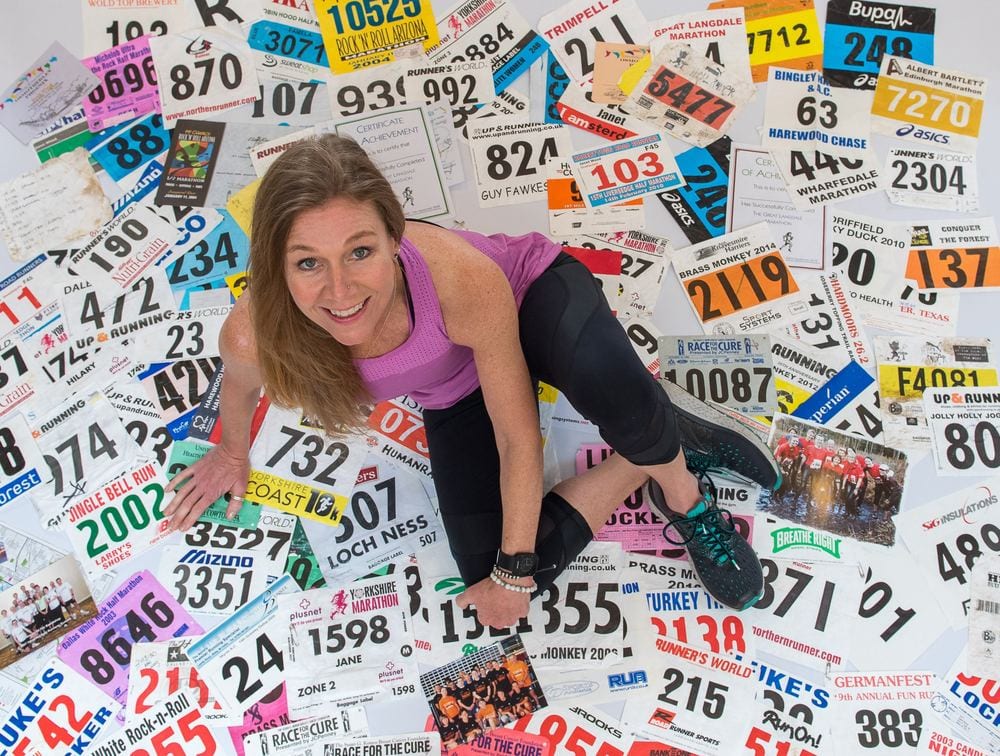 A female runner sits atop all her race numbers.