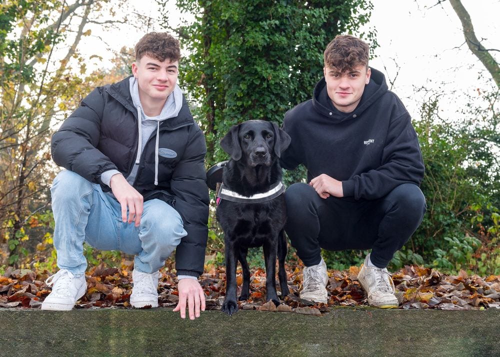 Teenage boys with their black labrador.